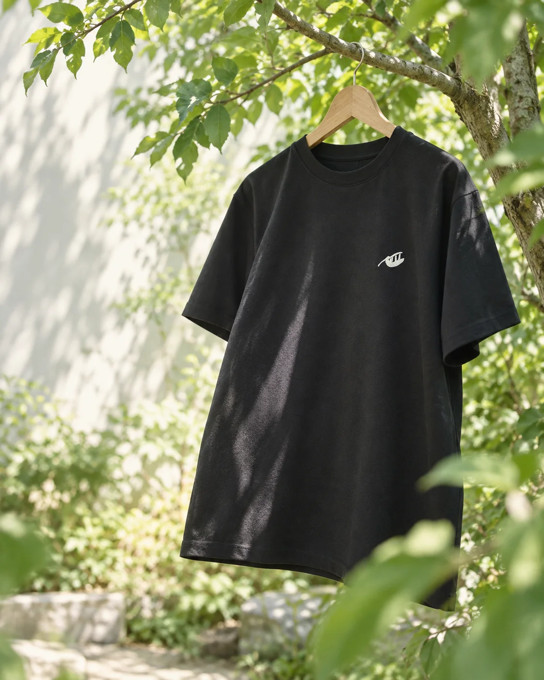 A black Namakemono T-shirt hanging among green trees