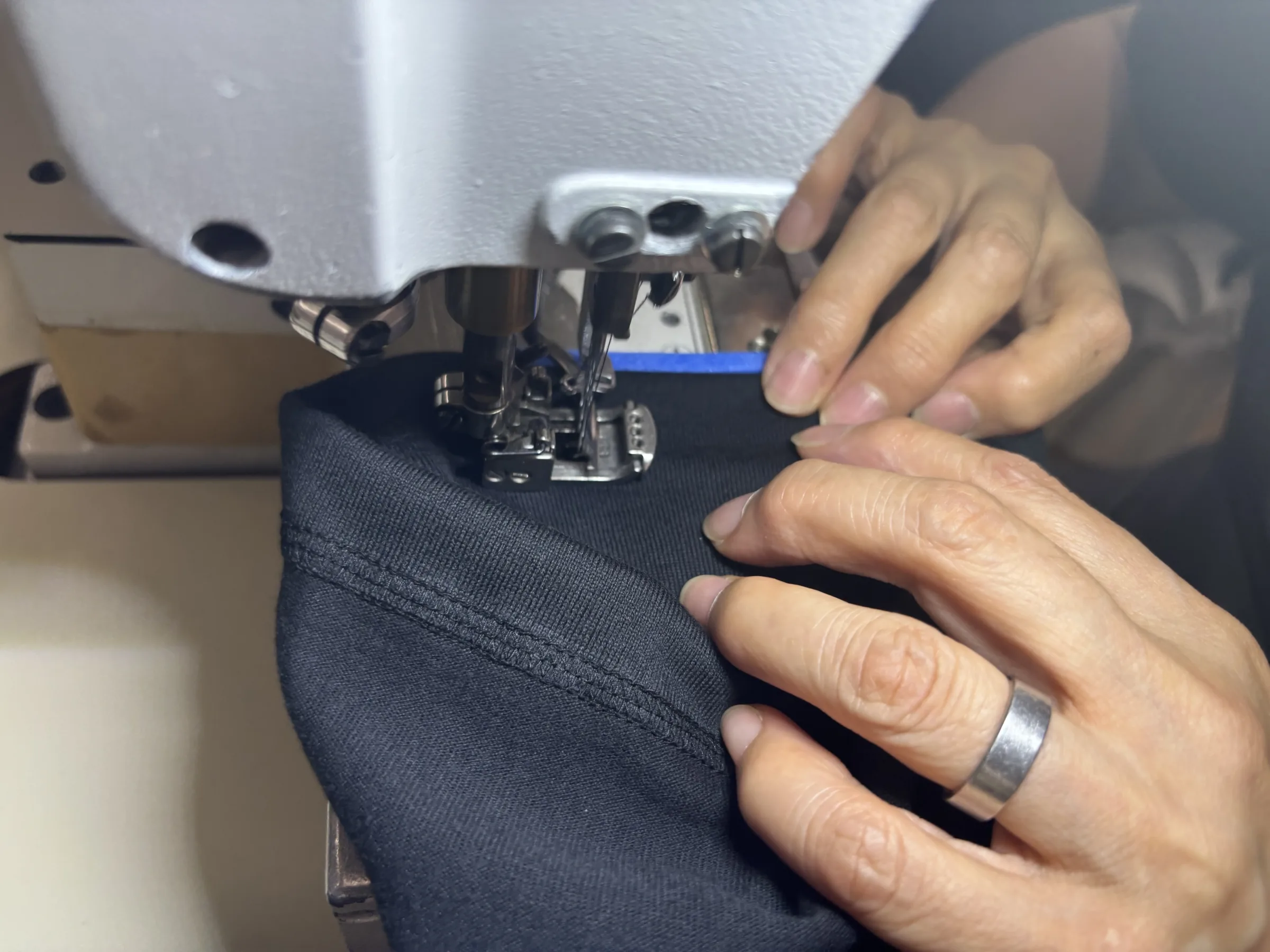 A maker guiding fabric through a sewing machine